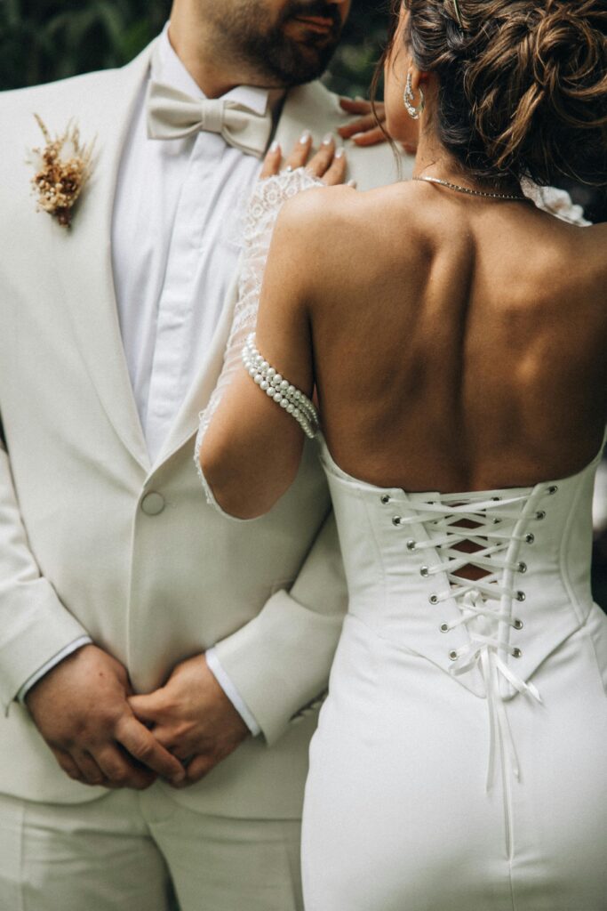Close-up of a couple in elegant wedding attire outdoors.
